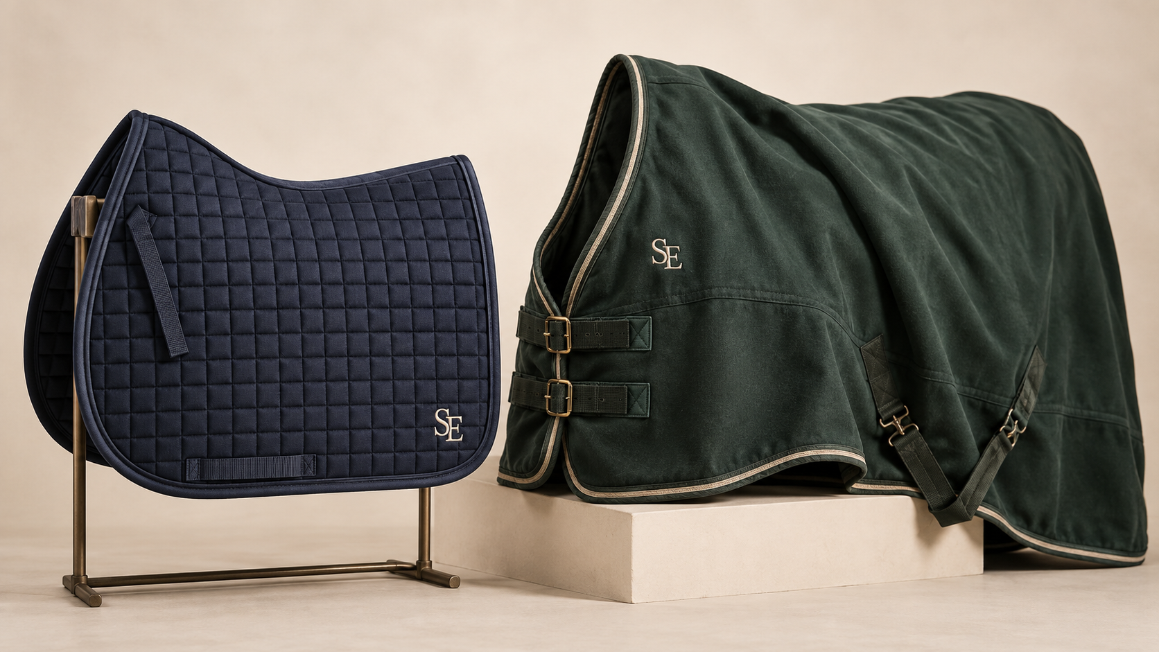 Navy saddle pad and forest-green horse rug with cream SE embroidered monograms in a studio setting